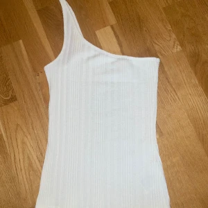 Vitt off shoulder linne med ett axelband  - Vitt linne med ett axelband. Väldigt fint skick!