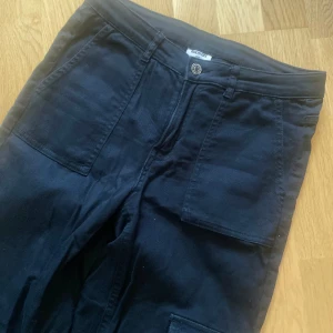 Svarta Cargobyxor  - Svarta Cargobyxor i storlek 170. Motsvarar en S eller Xs beroende på hur man vill att dom ska sitta. Raka i benen.