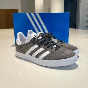 Adidas Gazelle - Ett par en-gångsanvända Adidas Gazelle skor i ljusgrå färg. Kvitto och låda finns kvar. Perfekta för våren!