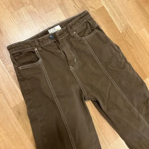 Raka bruna jeans  - Raka bruna jeans med vita sömmar och detaljer. Helt oanvända. Strl 36