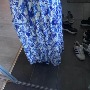Lång kjol  - En blå blommig lång kjol ifrån Lindex i storlek M för att få den längre går att spänna in vid midjan