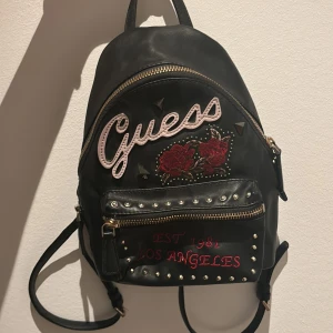 svart Guess väska  - Super bra skick, många fickor inuti, får plats med mycket, köpt för över 1200kr 
