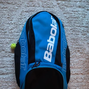 Tennisryggsäck babolat - Säljer en tennisväska från babolat i serien pure drive som tyvärr inte säljs längre. Köpt för 899kr säljer för 300kr , mycket fint skick och knappt använd. Ryggsäcken har plats för 1-2 racketar med skyddande fodral för handtaget. Flera andra fack!