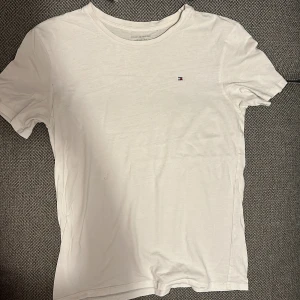 Tommy Hilfiger t-shirt - Vit bas t-shirt från Tommy Hilfiger, storlek är till 152/164 cm (barnstorlek) men funkar som XS/S. Kan förekomma någon liten fläck, som troligtvis går att få bort med Vanish el liknande medel.
