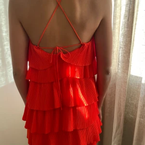 Orange röd volangkläning - Kort volangkläning, använd 3 ggr knytning i ryggen (går att vika in smörerna innanför kläningen och ha som off shoulder)