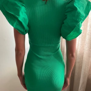 Grön kläning med piffig volang ärm - Tight ribbad kläning med piffig volangärm, funkar xs/s eftersom den är ganska tight