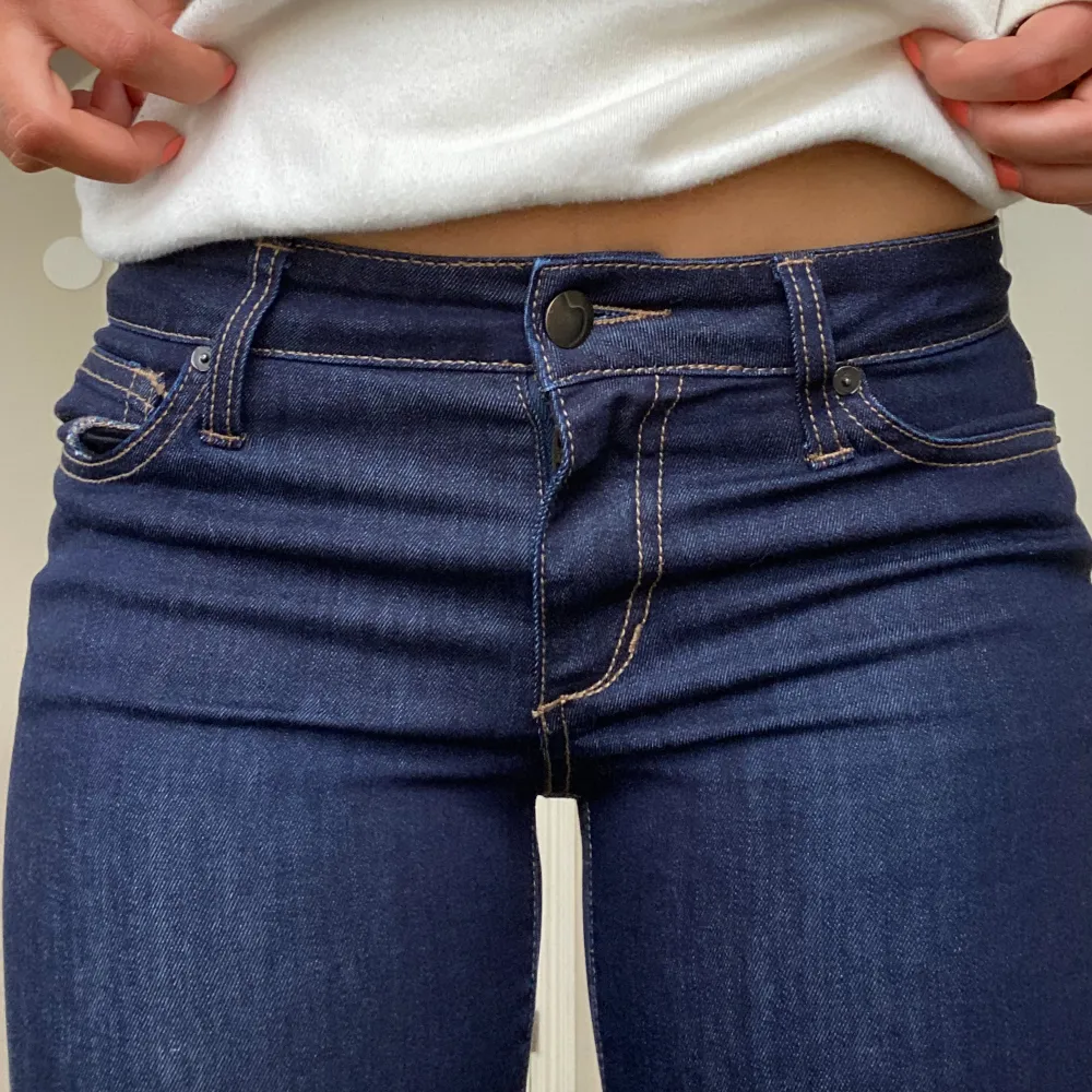 Ett par mörkblåa jeans med orangea sömmar! Dom är lågmidjade och utsvängda. Långa i benen på mig som är 168cm.  Innerbenslängd: 87cm Midja: 80cm. Jeans & Byxor.