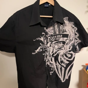 Extreme Couture Skjorta - Svart extreme couture skjorta kortarmad. Inga defekter förutom att den inte passar på mig längre😔 Strlk L men kanske passar mer åt det mindre hållet‼️