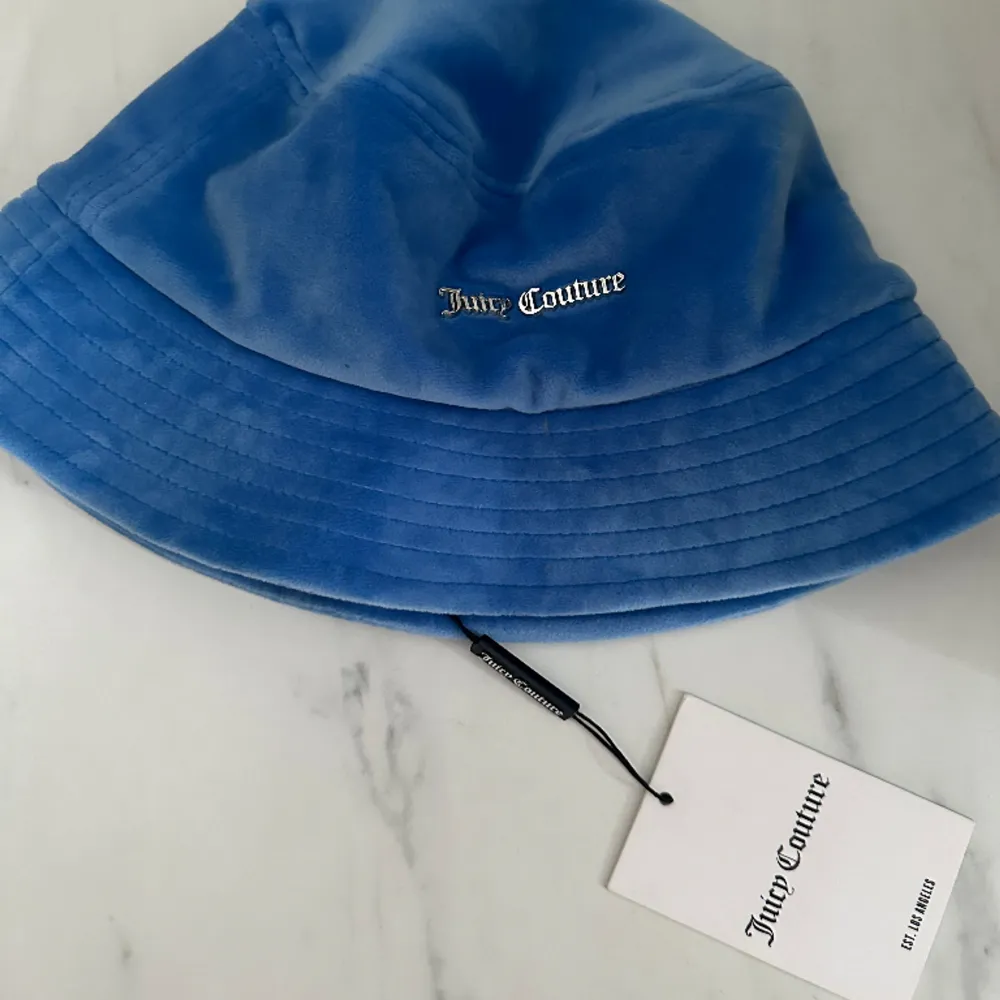 En blå bucket hat från juicy couture, passar perfekt till de mörkblå sättet🫶🏻  Helt oanvänd med prislappen kvar. Nypris: 500kr. Accessoarer.