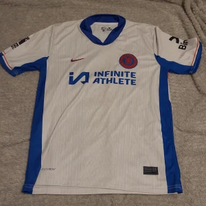 Chelsea tröja borta 24/25 - Chelsea tröja bortaställ 24/25,storlek M men passar även storlek L. Säljer för att den var liten för mig. Skön material och är aldrig använd. Skick 10/10 och perfekt för sommaren!