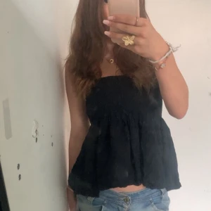 Svart Tubtopp - Svart tubtopp med volanger 🤍 Passar mig som ofta bär S, köpt här på plick men kommer ifrån Lindex! Kan även användas som kjol :)