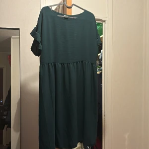 En mörkgrön klänning  - Oanvänd klänning, storlek 44, ungefär en meter lång.