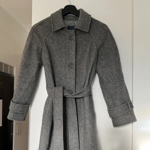 Grå kappa - Den perfekta grå kappan i 80% ull, perfekt till våren. Smått a-linje format men sitter snyggt och rakt/lite Oz på mig som är xs/34