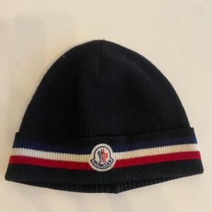 Moncler mössa - En moncler mössa i bra skick. Har inte användning för den längre och vill få den såld.