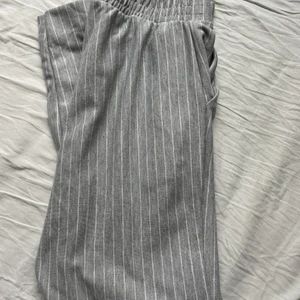 Randiga tygbyxor - Gråa tygbyxor med smala vita ränder. Köptes för några år sedan på new yorker i storlek M. De har framfickor och en liten slits där nere på benen som man kan se på bild 3. 