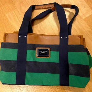 Tommy Hilfiger dam väska  - Tommy Hilfiger väska. Köpt för ett par år sen, knäppt använd och i nytt skick. Material: Läder och tyg. Från djur- och rökfri hem.  Ordinarie pris 1500kr Upphämtning Hägersten(Aspudden, Liljeholmen, Gröndal) alt Kungsholmen 