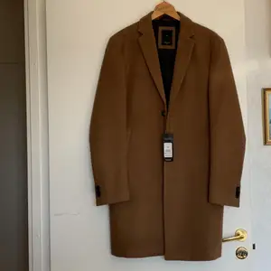 Stilig brun kappa från New Look, helt oanvänd med prislapp kvar! Herrstorlek M men passar unisex också :) Orginalpris 800kr