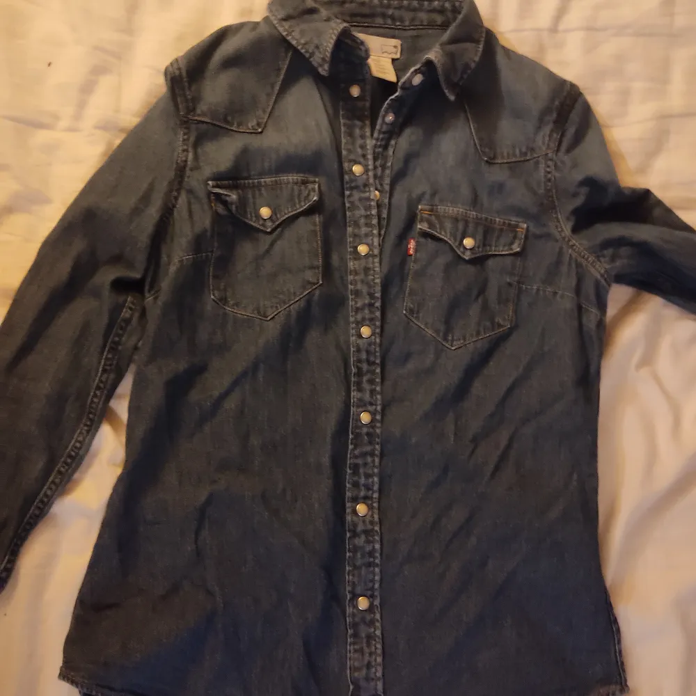 En skjorta in ett jeans liknande material och med plast knappar som inte syns så bra på bilderna men nu vet du :). Skjortor.