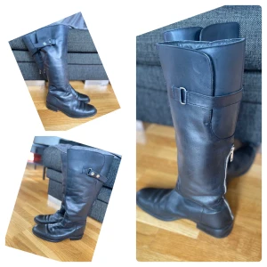 Höga stövlar - Svarta höga damstövlar med dragkedja bak och snygga spännen på sidan. St 40. I använt men gott skick. Hämtas av köparen. Betalas med swish. (Vid frakt står köparen för den kostnaden. 100kr