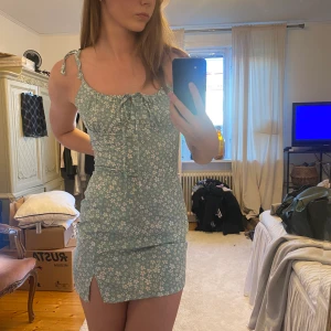 Sommar klänning - Turkos klänning med vita blommor. Materialet är ganska tunt. Fint skick! Jag är 172cm lång