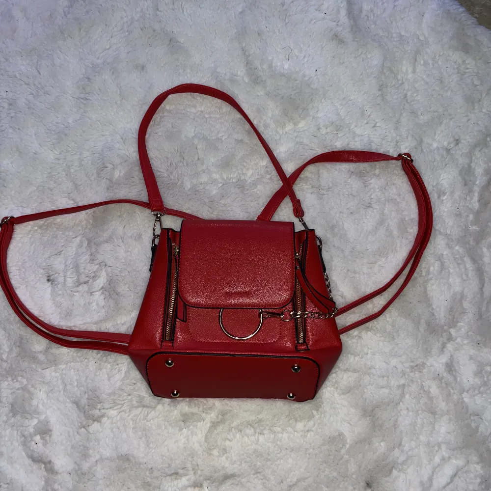 En röd väska som kan även användas som ryggsäck.. Väskor.