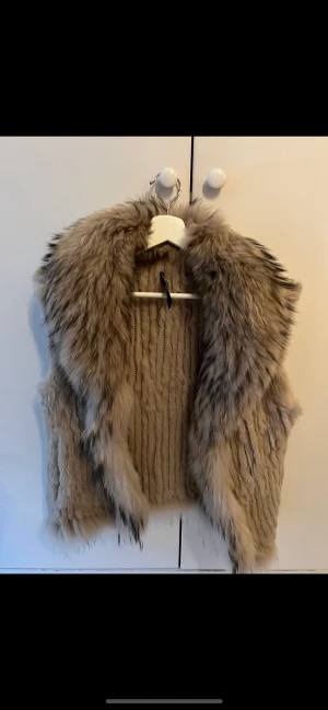 Pälsväst - Säljer denna beige/bruna Pälsväst! Storlek Small/Medium. Köpt i Sturegallerians gamla butik för 5 år sedan, knappt använd. Har även fickor och kan knäppas igen. Hittades i garderoben längst in nu under flytt. Ej använd på 2 år kanske men väldigt fin