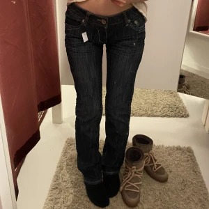 Lågmidjade jeans - Så snygga lågmidjade jeans!!  Midjemått: 76cm  Innerbenslängd: 80cm  I jättebra skick med tanke på att de är vintage, alla rhinestones sitter kvar på bakfickorna🥰