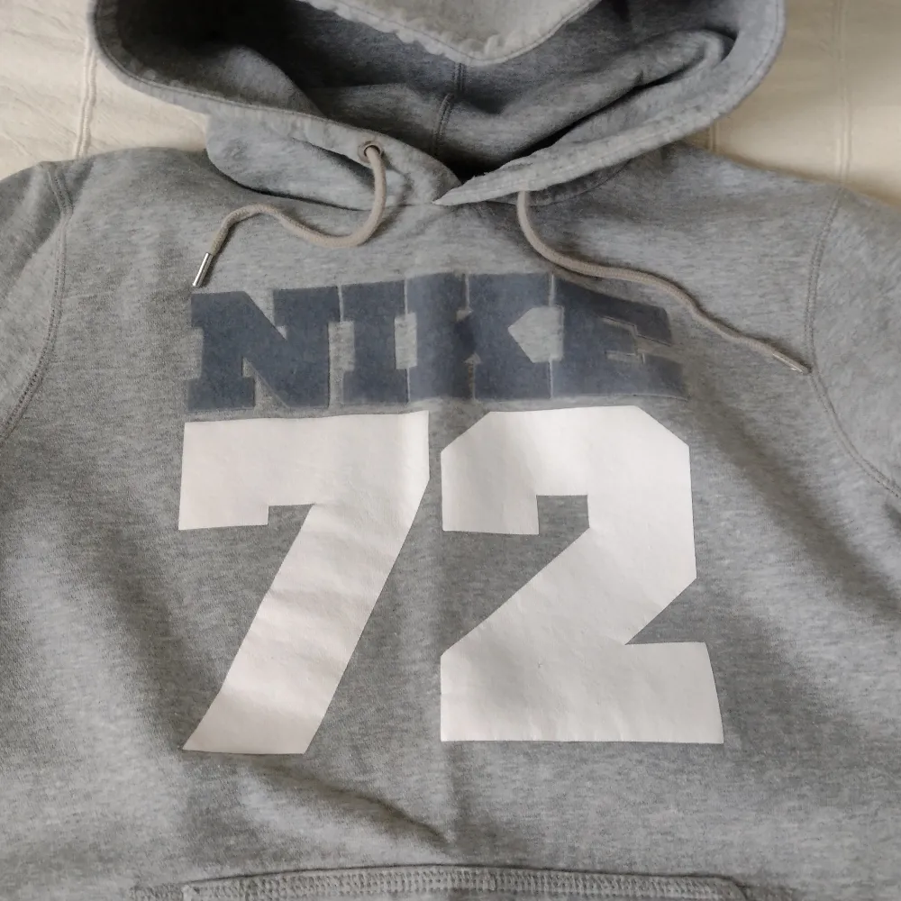 Intressekoll. Grå vintage Nike 72-hoodie. Storlek M. Skitsnygg och skön med stor huva. I fint skick men lite smånopprig på vissa ställen och litet märke/spricka i det vita trycket. . Hoodies.