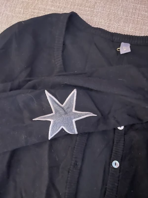 kofta med stjärnor  - säljer så cool svart kofta med gråa stjärnor på armbågarna! denna tröja är så snygg och populär och söka för att den inte kommer till användning längre! köptes för ca 200kr men säljs för 75kr+frakt!🖤