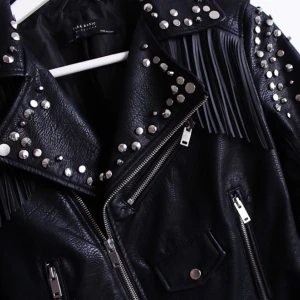 Skinnjacka med fransar och nitar - Skinnjacka med fransar och nitar. Oäkta läder. Från Sara. Oanvänd. 