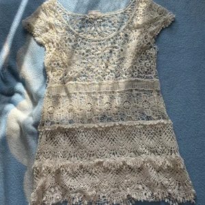 Klänning i Spets - Klänning/tunika i vit spets. Super fin och i bra skick men kommer helt enkelt inte till användning. Passar att ha över tex en vit topp o kjol eller klänning. Eller kanske över en bit bikini på stranden. Storleken är men men tror den kan passa en L också 