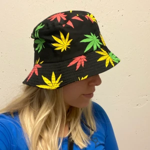 Kul för halloween  - Bucket hat/ fiskehatt säljes med plantor i rött, grönt & gult. Aldrig använd så fint skick. Kul som halloween outfit eller om man gillar dessa plantor. 