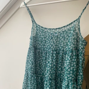 Grönt blommigt linne - Ett skitfint linne från Hm, typ smaragd grön med vita blommor. Färgen är mer klar grön i verkligheten, tyvärr lite för lite så därför säljs de. St 32