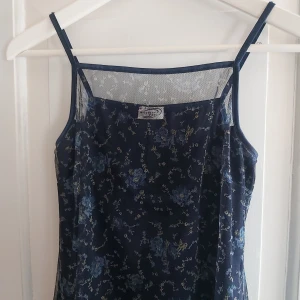 Småblommig miniklänning i 90-talsstil - Småblommig miniklänning från vintage butik (Sputnik) i Budapest. 90-tals stil med mörkblå underklänning och genomskinligt, småblommigt tyg över. 