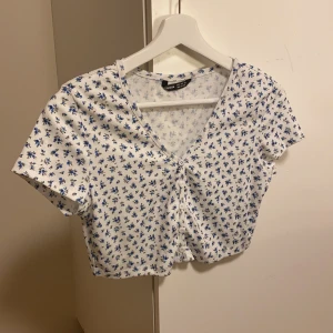 Vit tshirt med små blommor - Supersöt croppad tshirt med små blåa blommor. Aldrig använd
