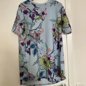 T-shirt klänning i superfina färger och blommigt mönster! Den har en fläck som tyvärr inte går bort i tvätt (bild 2), fast den är inte vidare synlig. Har också blivit nopprig efter användning och tvätt (bild 3).