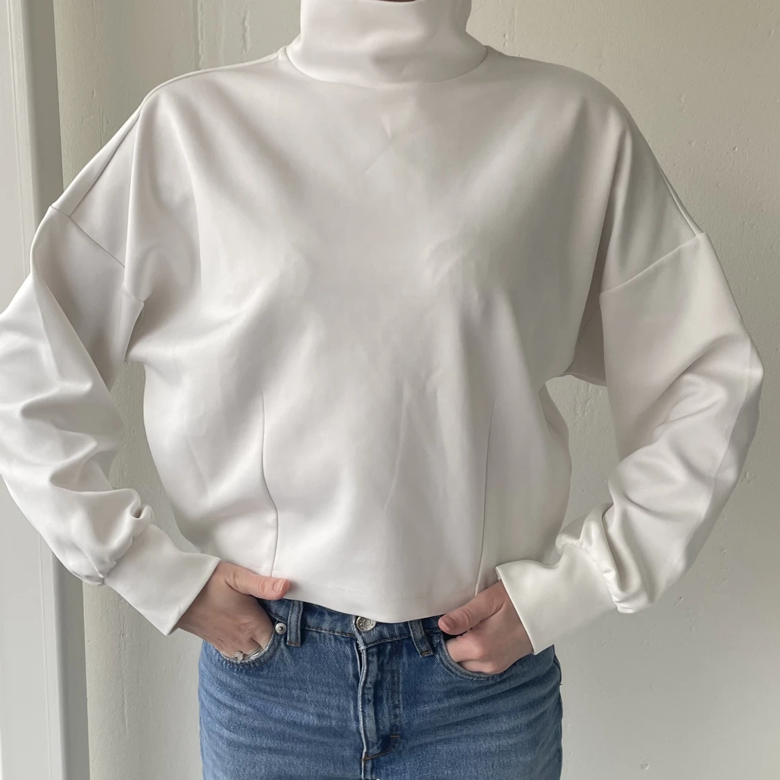 Vit cropped långärmad med hög krage.