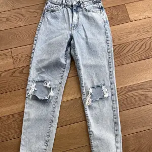 Ljusblå jeans från Gina Tricot med hål på båda knäna i storlek 32=xss 