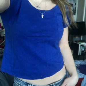 Söt t-shirt - En lite kortare t-shirt med en gullig ficka som slutar snyggt strax nedanför naveln. Använd men i bra skick💙 Strlk 34, skulle säga att den passar en xs-s, jag är 160 cm :) 