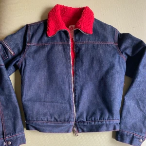 Fodrad jeansjacka  - En fodrad jeans jacka, som slutar där byxan börjar. Har fickor röda sömmar och rött foder. As najs men säljer pg för mycket jackor hemma. Passar en 34-36a