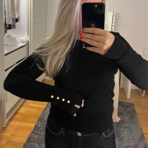 Svart finstickad tröja - Oanvänd finatickad tröja med guldiga knappar.