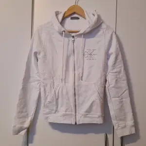 Vit zipup hoodie från Calvin Klein, silver dragkedja med CK tryck på bröstet, strl M. 