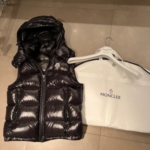 Moncler vest ”Bromes”  - En riktigt snygg Monclervest, helt oanvänd. Luvan går att ta av. Storlek ”2” vilket är ungefär S/M.  Köpt på NK ca 3 månader sedan. Nypris ligger på Ca 9000kr. För mer bilder hör gärna av er! 