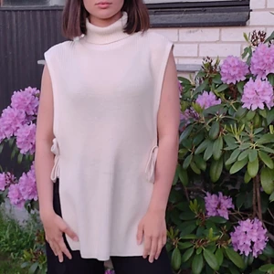 Stickad lång topp!  - En mysig och fin topp som passar till allt, utan armar och med charmiga rosetter på sidan. Använt enda 1 gång, den är som ny! Inköpspris 350kr 