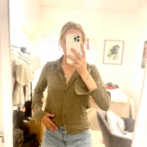 Skjorta - Något u-ringad skjorta. Längre bak.