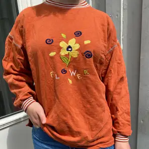 Retro tröja i fin orange färg med broderad text och blommor. Storlek M ungefär.