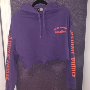 Croptop hoodie - En hoodie i croptop format, på armarna står det ”female future”, på framsidan står det ”babe squad brooklyn”, på baksidan står det ”babe squad” med en drake. 
