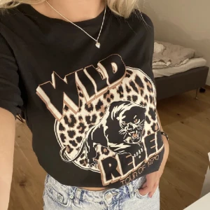 Tshirt - Svart T-shirt med tryck i leo från Gina strl s. Vikt in den kortare på bilderna. Baksidan är bara enfärgad svart. Kan fraktas.