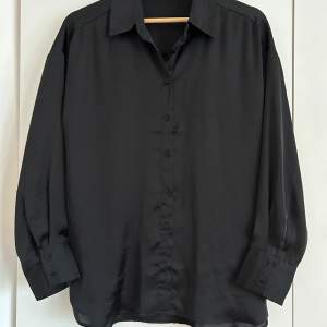 Superfin svart satinskjorta i jättbra skick. Oversize fit. Length: 69 cm in size S
