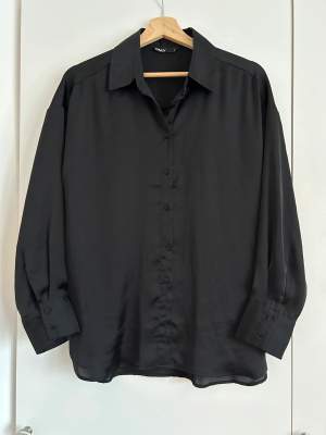Superfin svart satinskjorta i jättbra skick. Oversize fit. Length: 69 cm in size S